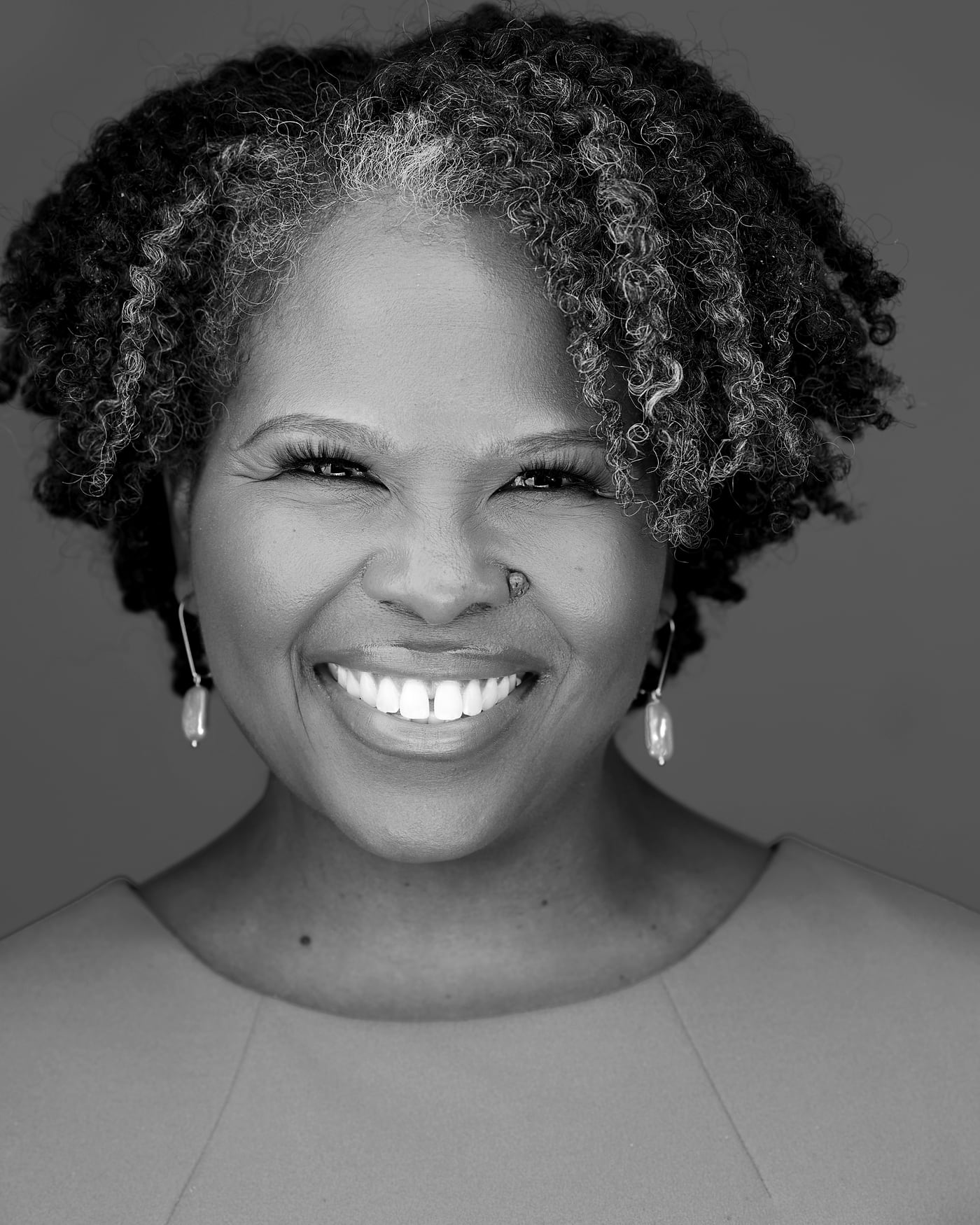 Black-and-white fine-art portrait of a woman with natural silver and black curls.