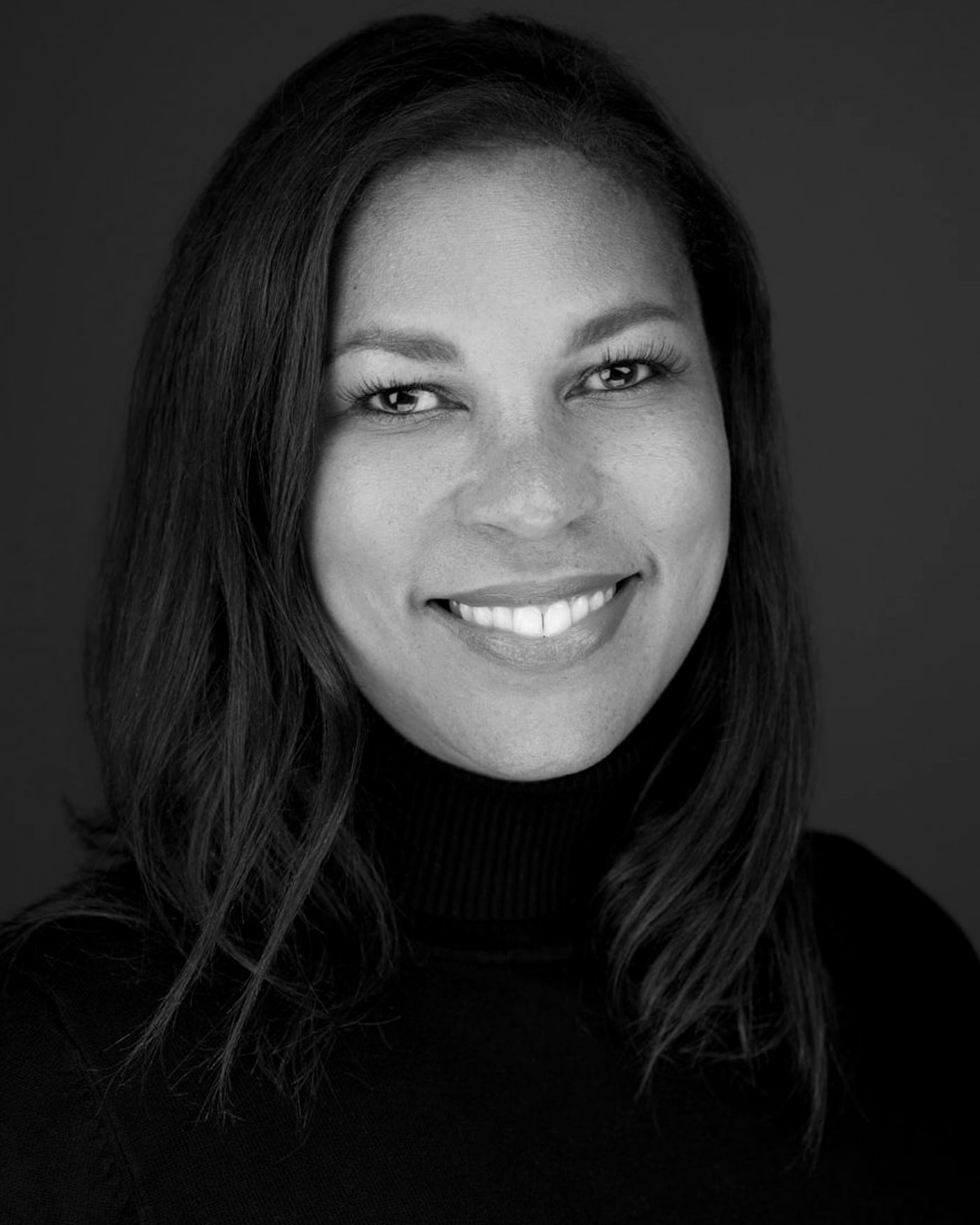 Black-and-white fine-art portrait of a woman in a turtleneck against a dark background.